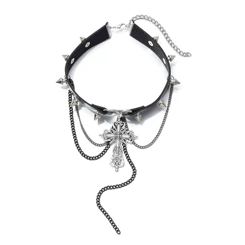 Choker gótico negro con dije de cruz barroca, corazón central y cadenas colgantes.