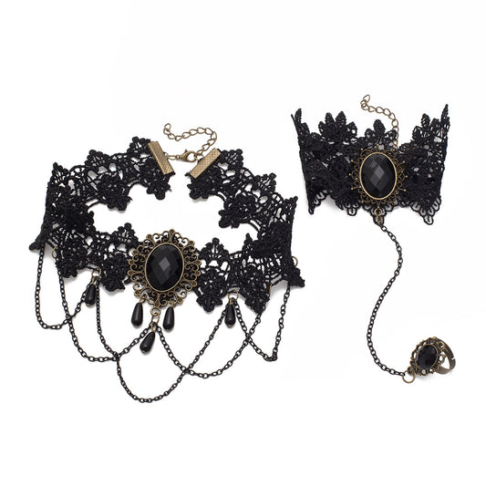Vista plana del conjunto de encaje estilo victoriano con gemas negras y herrajes bronce.