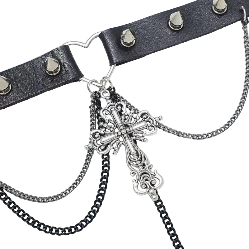 Primer plano de la cruz barroca detallada, los picos y las cadenas del choker alternativo.