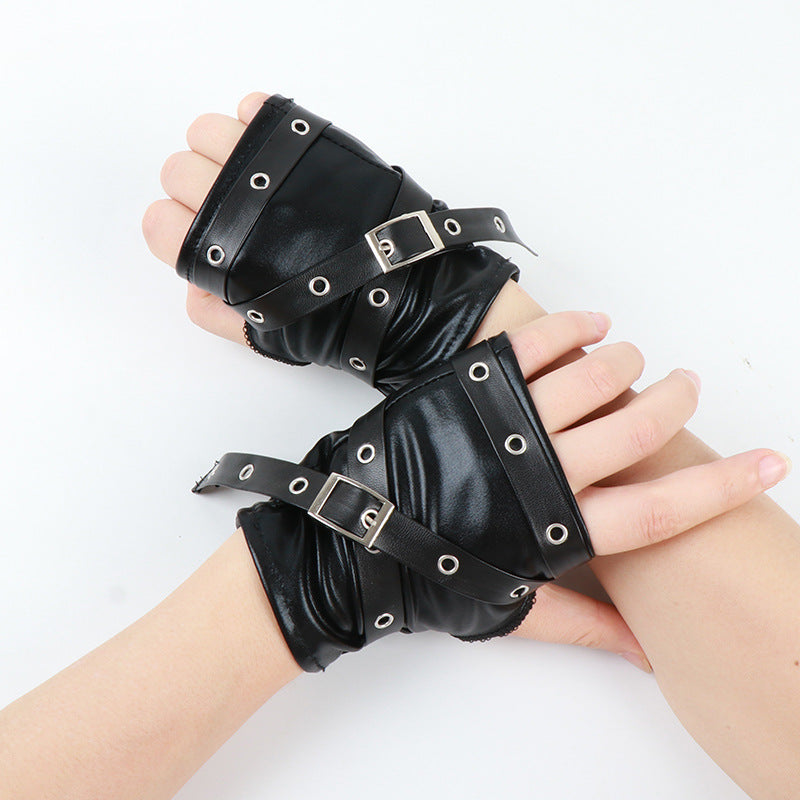 Primer plano de guantes para mujer sin dedos de piel negra con hebilla y ojillos metálicos.