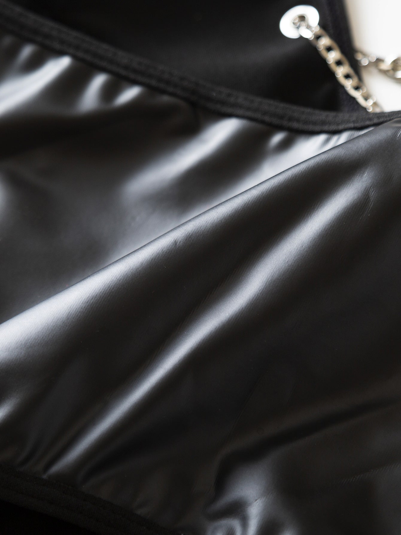 Detalle de la textura premium de piel sintética negra con acabado satinado y suave.